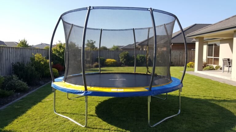 Round trampoline with a safety enclosure net set up on a grassy suburban backyard lawn