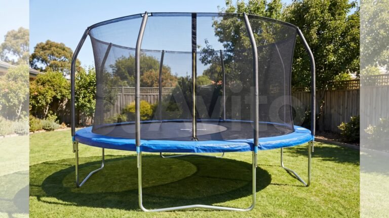 Round backyard trampoline with blue protective padding and tall mesh enclosure net on a grassy lawn