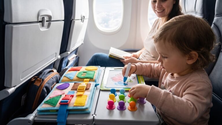Toddler playing with mess-free busy boards and drawing toys on an airplane tray table during a flight